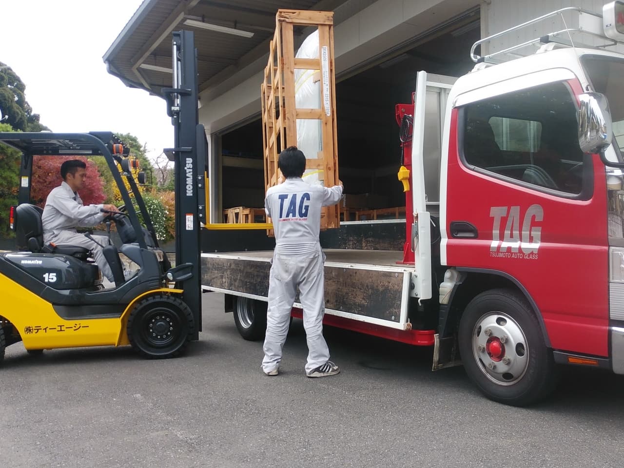 フォークリフトで輸送用トラックに交換用のガラスを積み込んでいる